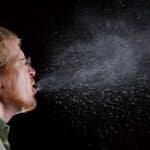 Man mid-sneeze, a common symptom when comparing cold vs flu vs RSV