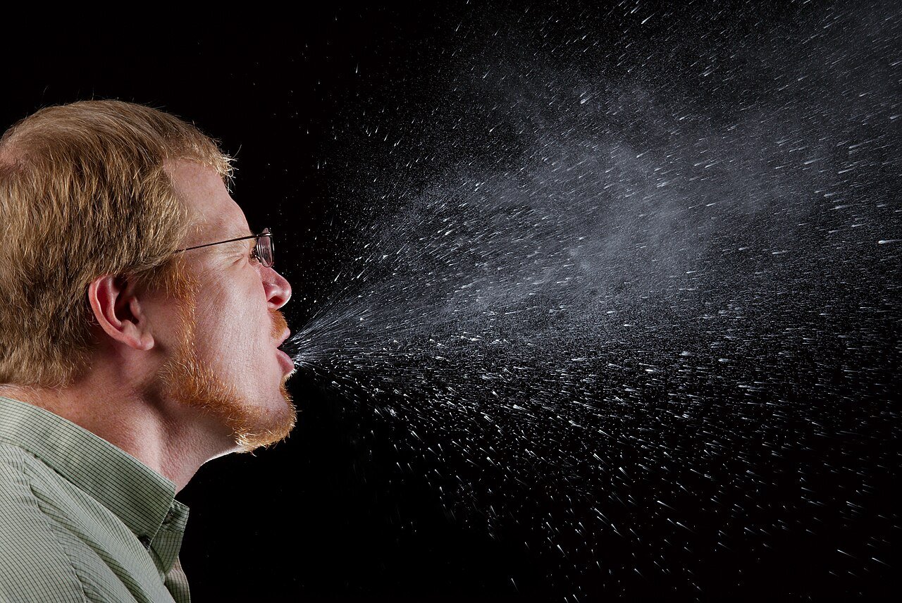 Man mid-sneeze, a common symptom when comparing cold vs flu vs RSV